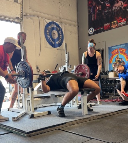 Narayana benching at a Colorado Strength Coalition meet, spotters either side