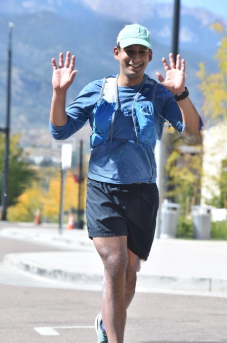 Narayana running, arms up, on a road with mountains behind him